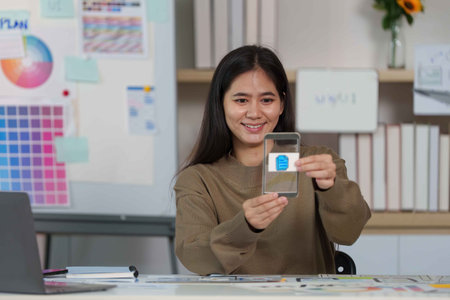 Smiling Designer Showcasing Mobile App Interface on Smartphone.の写真素材