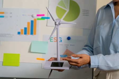 Renewable Energy Model. Businesswoman showcasing wind turbine model for ESG presentation.の写真素材