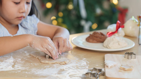 Christmas cookie preparation. A young girl uses cookie cutters to create festive shapes.