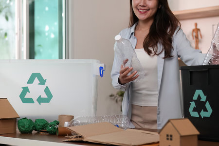 Sustainability. Woman recycling plastic bottles and cardboard in eco-friendly home.の写真素材