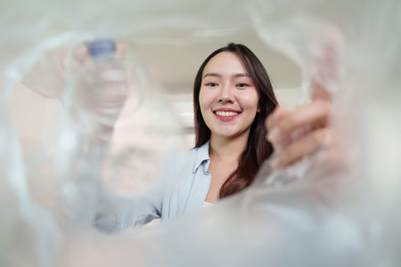 Recycling focus. Woman smiling while holding a plastic bottle.の写真素材