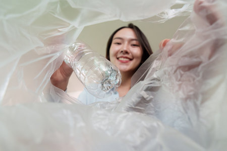 Sustainability. Woman recycling plastic bottle, promoting eco-friendly habits.の写真素材