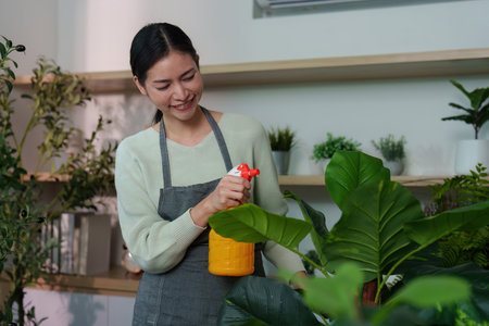 Indoor Gardening. Woman caring for houseplants with spray bottle.の写真素材
