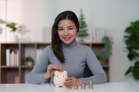 Financial Responsibility: Woman Smiling with Piggy Bank and Coinsの写真素材
