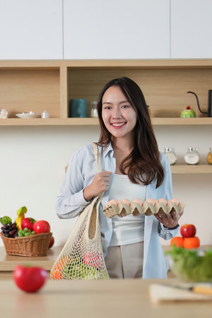 Sustainability Focus: Smiling Woman Holding Fresh Eggs and Vegetablesの写真素材