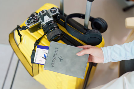 Travel Planning. Preparing for a trip with a suitcase, camera, and passport in hand.の写真素材