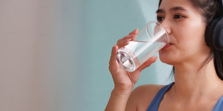 Wellness. Woman drinking water, promoting hydration and healthy living.の写真素材
