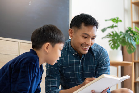 Father and Son Bonding. Engaging in a joyful reading session at home.の写真素材