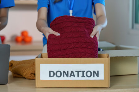 Donation Activity. Volunteer placing a sweater into a donation box.の写真素材