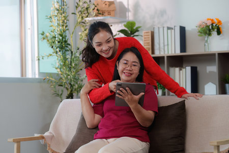 Digital connection. Young woman and her mother sharing moments on a tablet.の写真素材