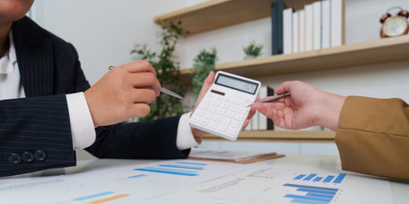 Financial Analysis. Professionals using calculator and documents for financial review.の写真素材