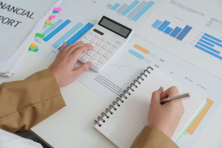 Financial Analysis. Professional reviewing financial report with calculator and charts.の写真素材