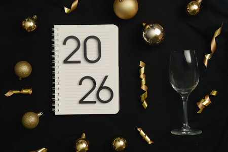 Celebratory New Year 2026 setup with notebook and glassの写真素材