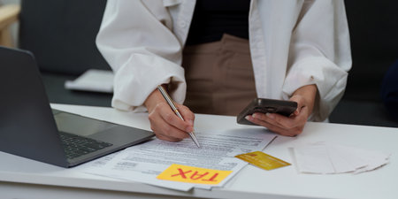 Tax filing. Woman calculating expenses while preparing tax documents.の写真素材