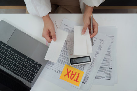 Tax documentation. Reviewing receipts and using a calculator for tax filing.の写真素材