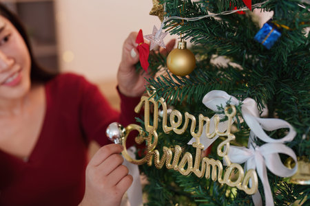Woman decorating tree with Merry Christmas sign and ornamentsの写真素材