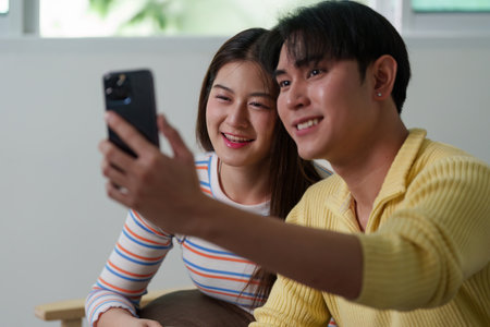 Couple taking a selfie together with smartphones at homeの写真素材
