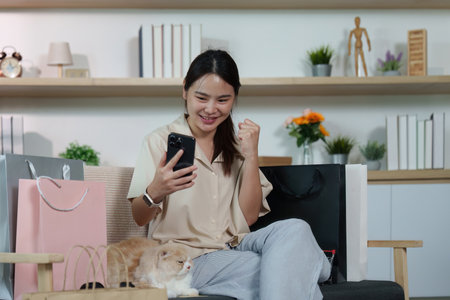 Joyful Shopping. Woman celebrating successful online purchase with smartphone.の写真素材