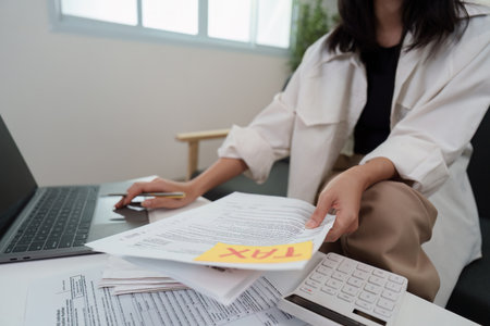 Tax Management. Individual sorting tax papers with calculator and laptop.の写真素材