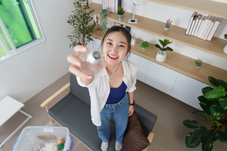 Recycling awareness. Young woman smiling while holding a plastic bottle for recycling.の写真素材