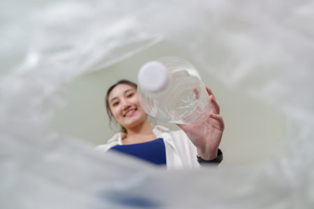 Recycling perspective. View from inside a trash bag as a woman drops a plastic bottle.の写真素材