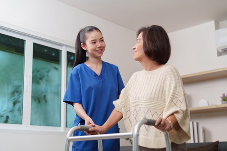 Caregiver assisting elderly woman with mobility supportの写真素材