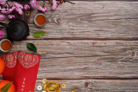 Chinese New Year celebration with tea, oranges, and red envelopes on wooden tableの写真素材