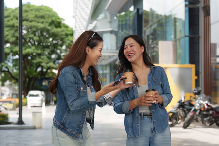 Friendship and Joy. Two young women enjoying coffee and laughter outdoors.