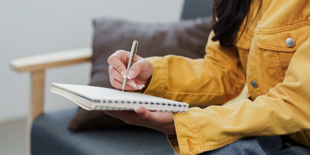 Lifestyle. Young woman writing in a notebook at home.