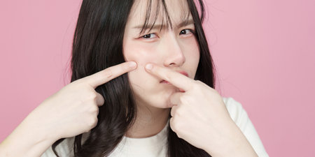 Skincare Concern. Young woman expressing frustration with acne on pink background.の写真素材