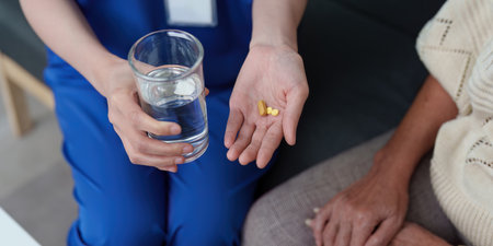 Healthcare. Nurse offering medication and water to elderly patient.