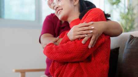 Emotional Connection. Two women sharing a warm embrace indoors.の写真素材