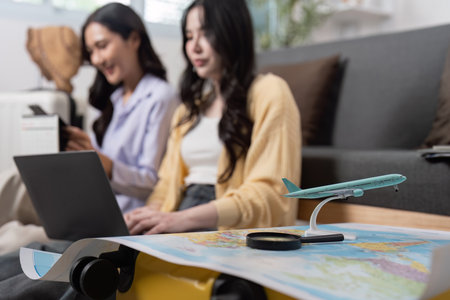 Travel Planning: Friends researching destinations with laptop and map