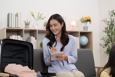 Travel Planning. Woman writing packing list while preparing suitcase.の写真素材
