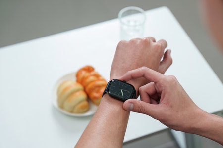 Individual checking smartwatch while enjoying snacks.
