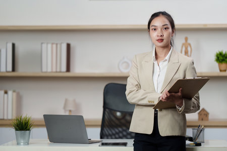 Working women holding clipboard in professional office environmentの写真素材