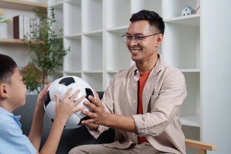 Family Life: Father and son playing with a soccer ball at homeの写真素材