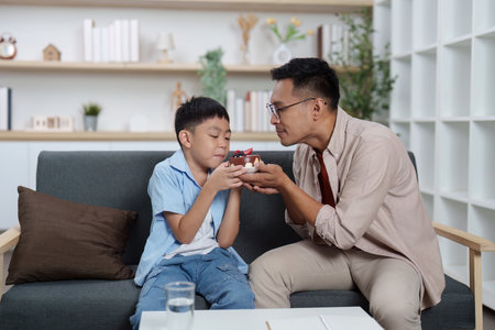 Family Life: Father and son sharing a joyful moment with a gift at homeの写真素材