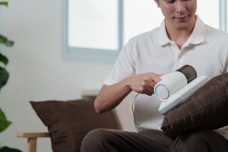 Technology and Lifestyle. Man using handheld vacuum cleaner for home cleaning.の写真素材