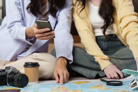 Travel Planning: Friends using a smartphone and map for trip detailsの写真素材