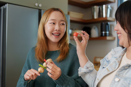 Healthy Cooking. Friends enjoying food preparation and sharing smiles in the kitchen.の写真素材