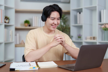 Remote Work. Young man wearing headphones while participating in a video call on his laptop.