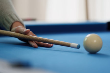 Billiards Game. Close-up of a player preparing to strike the cue ball on a blue pool table.