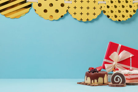Birthday background with lit candle cake gift box and garland on blue