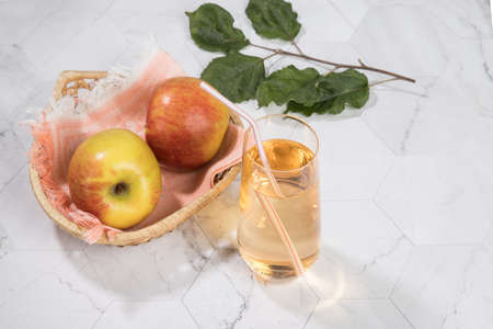 Apple juice in a glass glass, apples in a wicker plate on a light background. A place for copy space.Horizontal orientationの写真素材