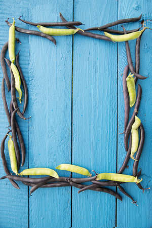 Pea and bean pods lie on a wooden background in the form of a frame-a source of vegetable protein. The concept of healthy eating. Vertical orientation.Place for copy spaceの写真素材
