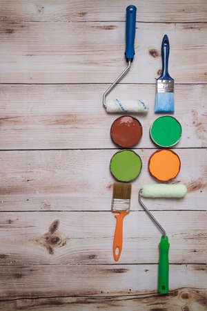 Paints, brushes and rollers for painting are laid out in the form of a still life on a wooden background. The concept of DIY repair. A place for a copy of space. Vertical orientationの写真素材