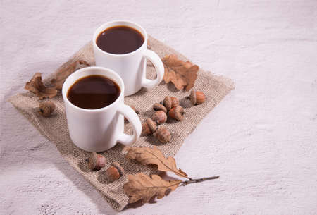 Glass coffee cups made of acorns on a napkin with acorns and oak leaves on a light background. Alternative to coffee, close-up. Copy spaceの写真素材