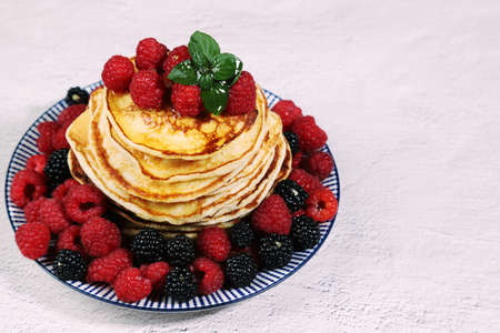Delicious dish of Russian cuisine-homemade pancakes with raspberries and blackberries on a light background.Copy spaceの写真素材