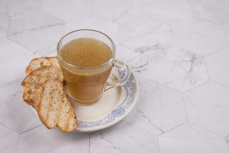 A Cup of hot meat broth for lunch with toasted white bread on a light background. Copy spaceの写真素材